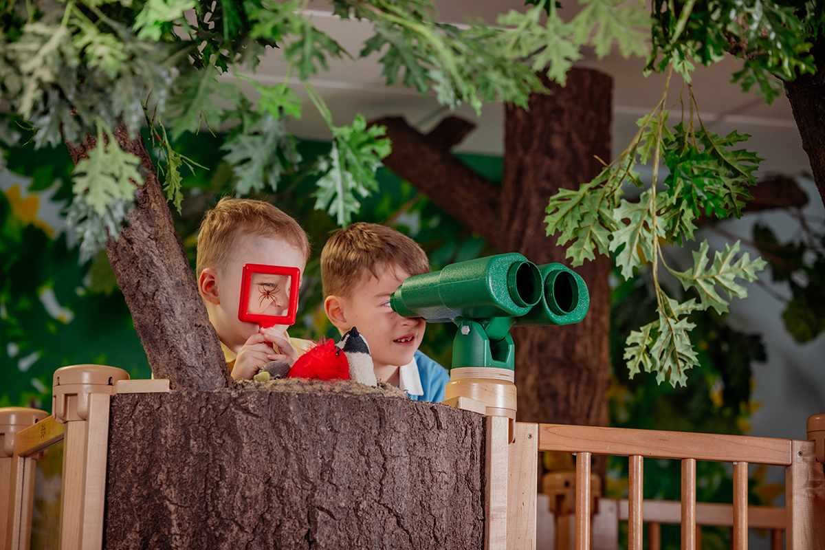 2 young boys look out over the top of the treehouse