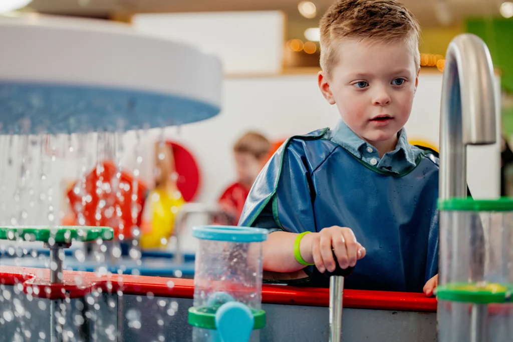 Young boy playing with water exhibit