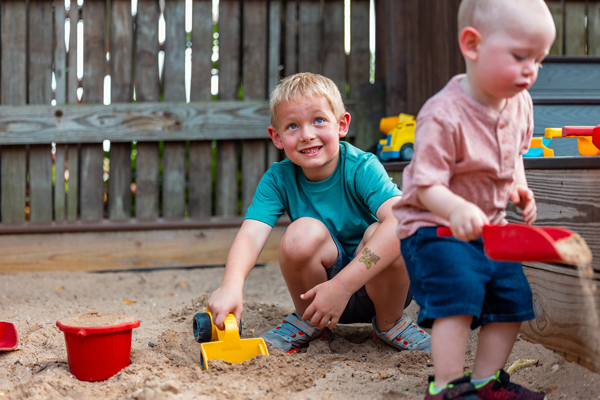 Young boy and toddler playing in sandbox