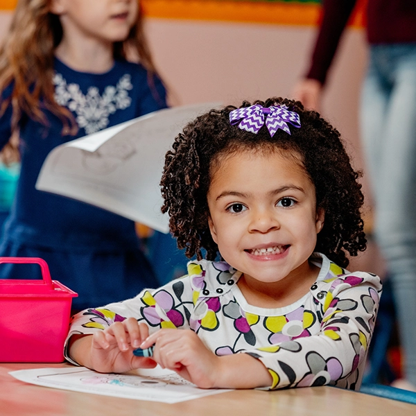 young girl coloring at table