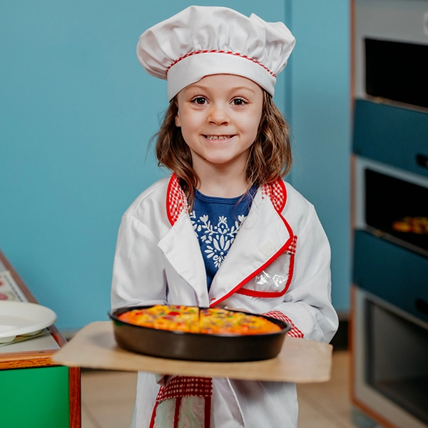 young girl dressed as chef with pizza