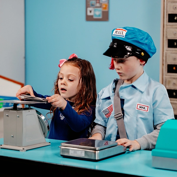 2 kids playing at being postal workers and weighing mail