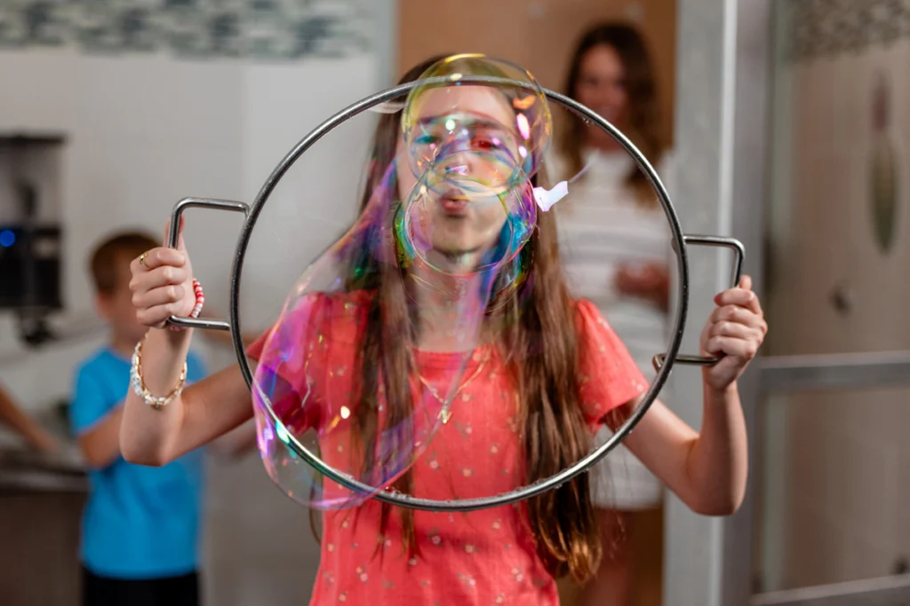 girl blowing bubble at camera in bubble exhibit