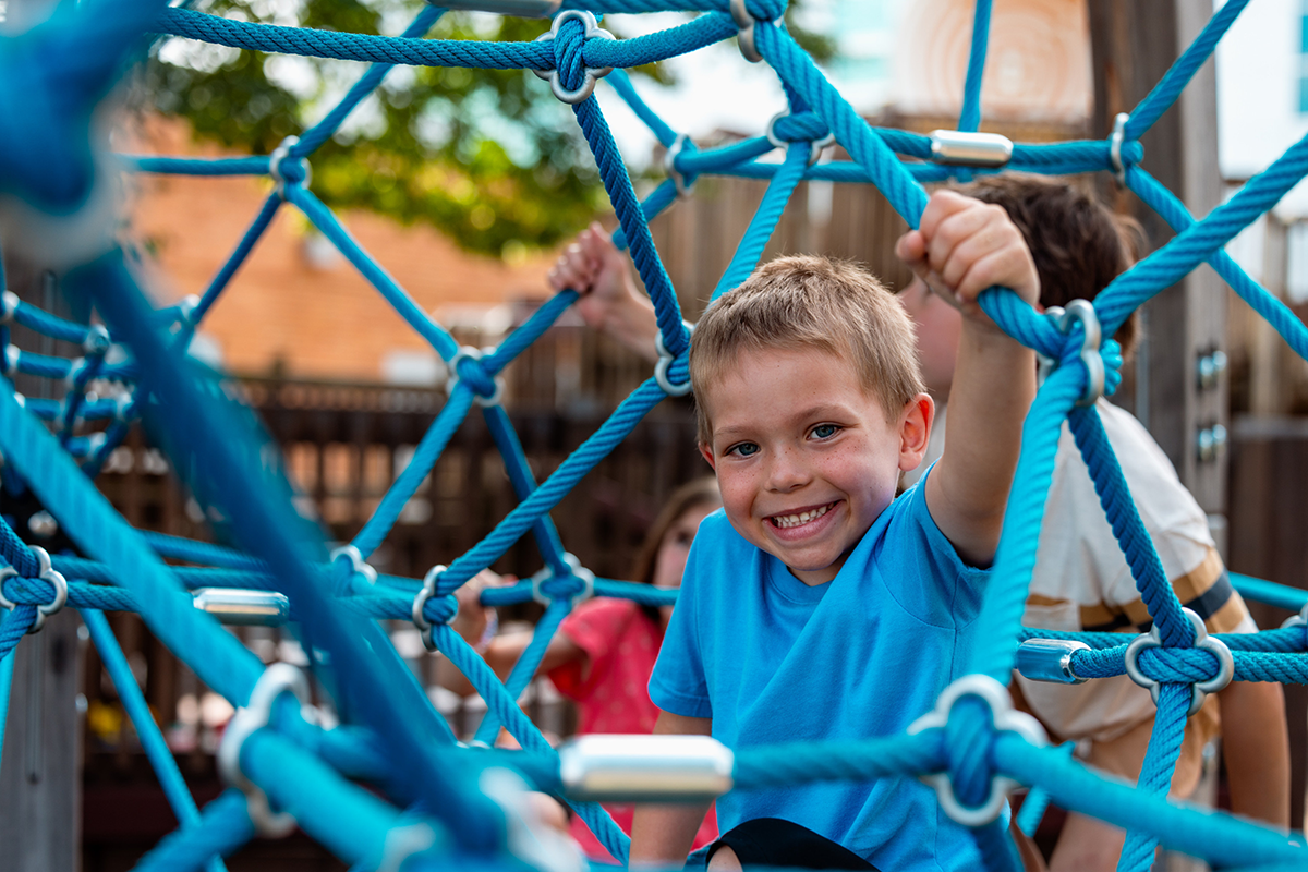 young boy playing on rope jungle gym