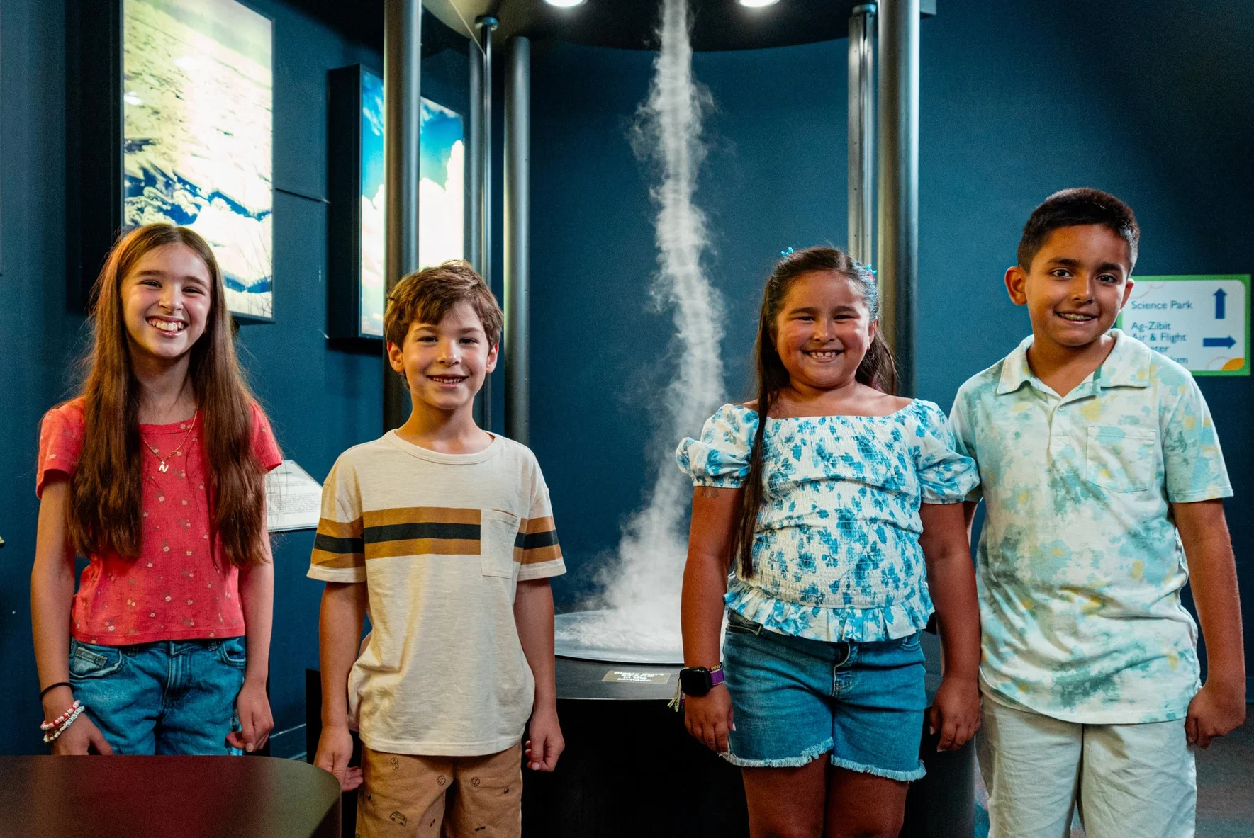 a group if kids smile at camera in front of tornado machine