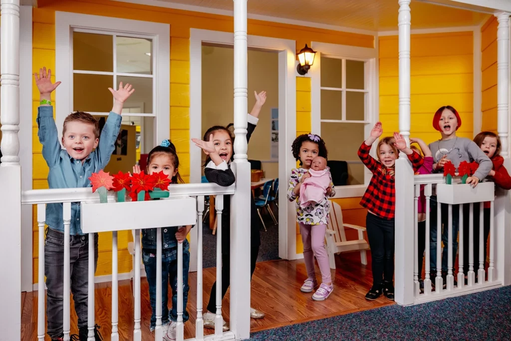 a group of children wave from house in museum exhibit