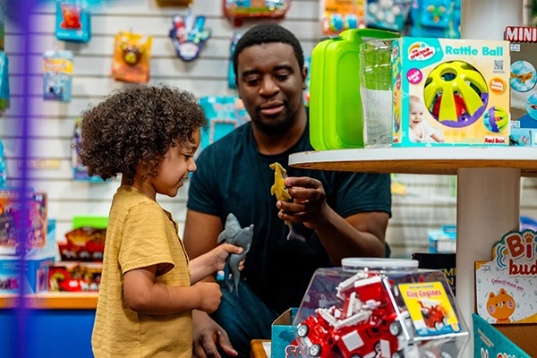 Dad shows to toy to daughter in gift shop